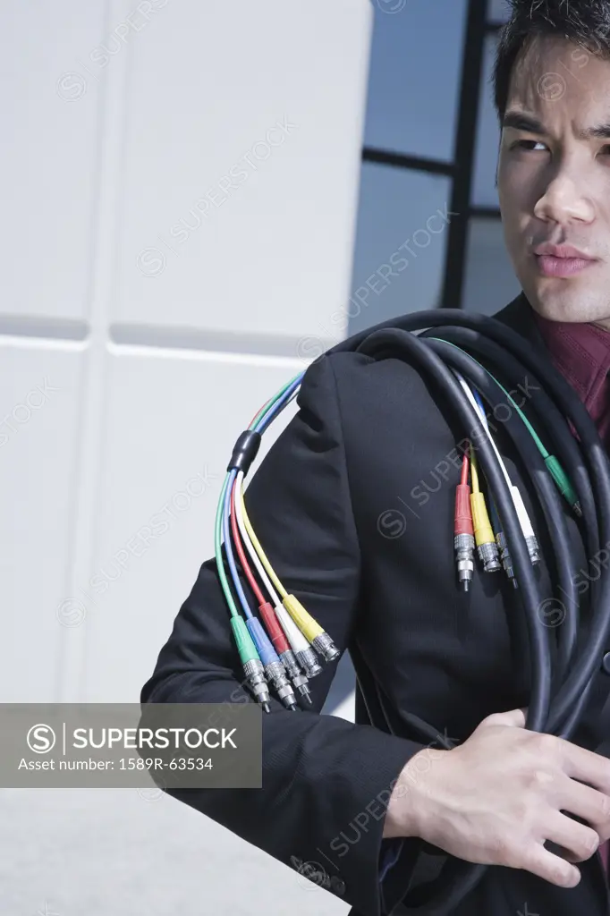 Asian businessman holding computer cable outdoors