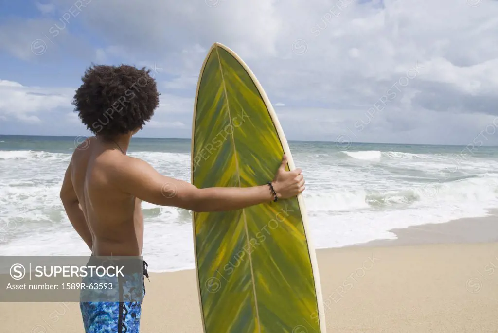 African man at beach with surfboard