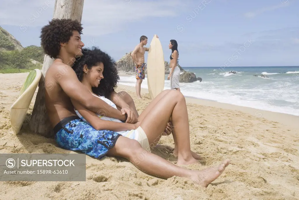 People relaxing at beach with surfboards