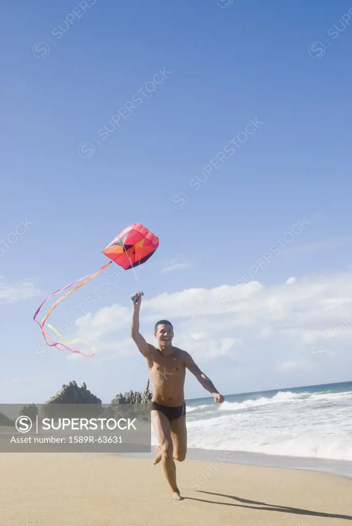 Hispanic teenager flying kite at beach