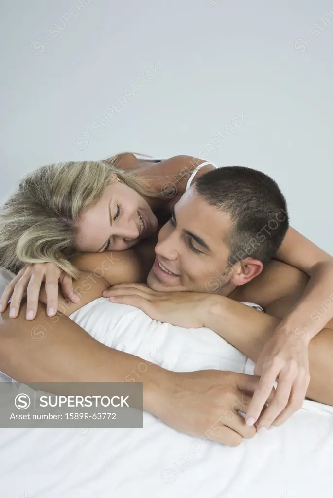 Smiling Hispanic couple laying in bed