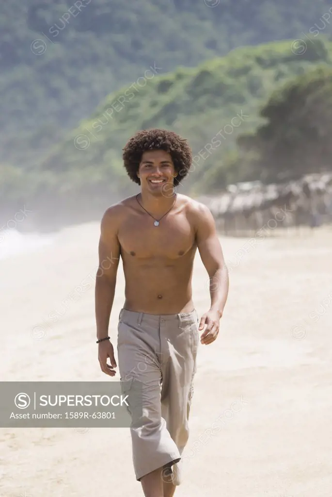 Hispanic man walking on beach