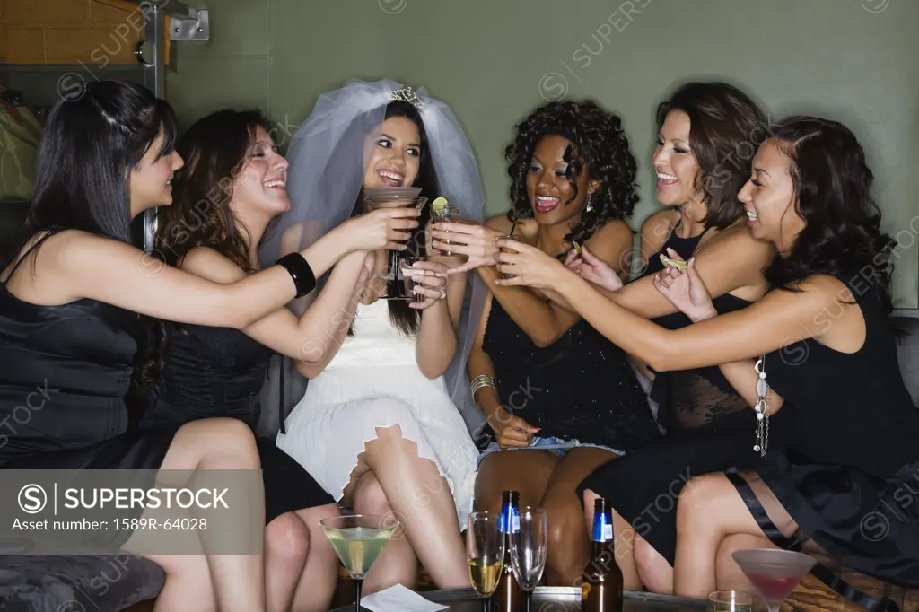 Friends drinking cocktails with bride in nightclub