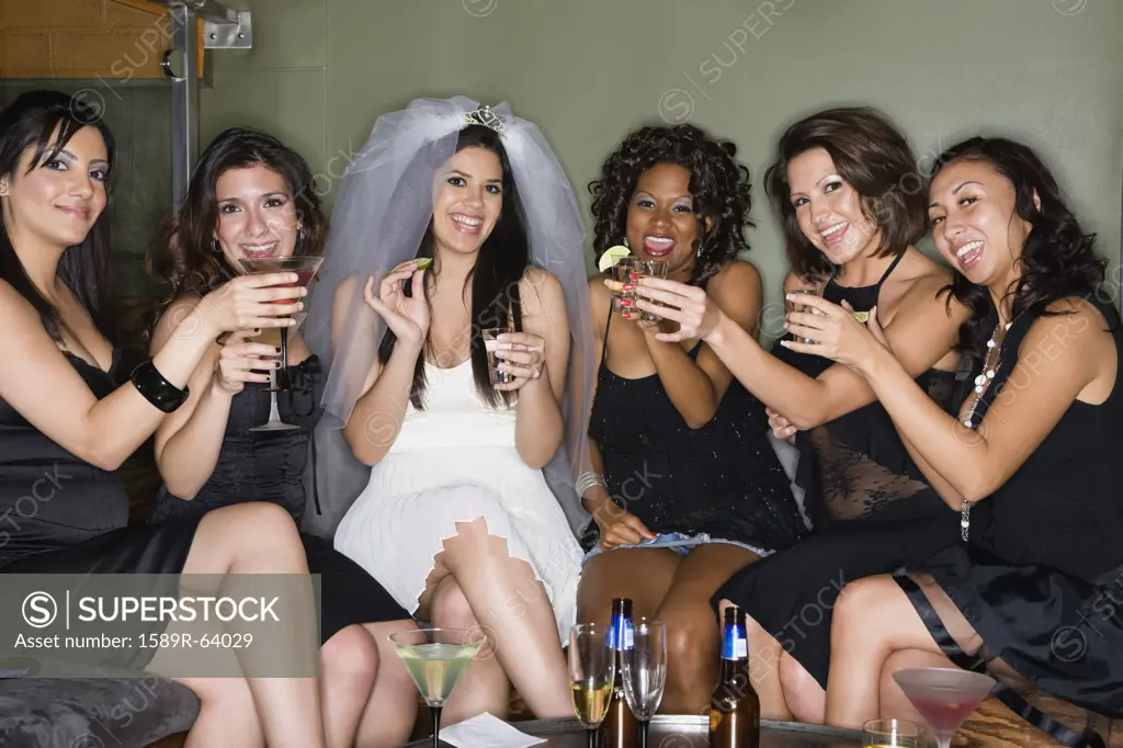 Friends drinking cocktails with bride in nightclub