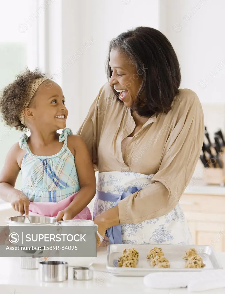 African grandmother baking cookies with granddaughter