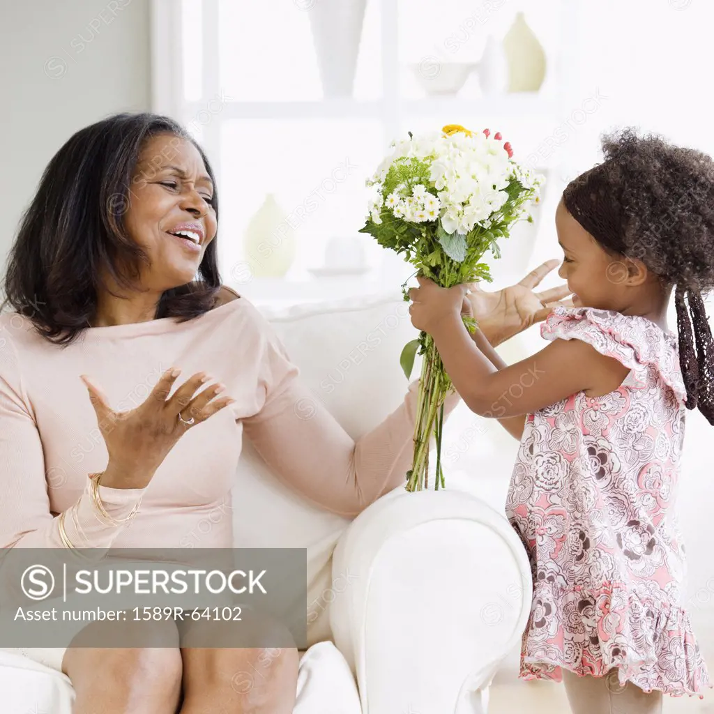 Granddaughter giving African grandmother bouquet of flowers