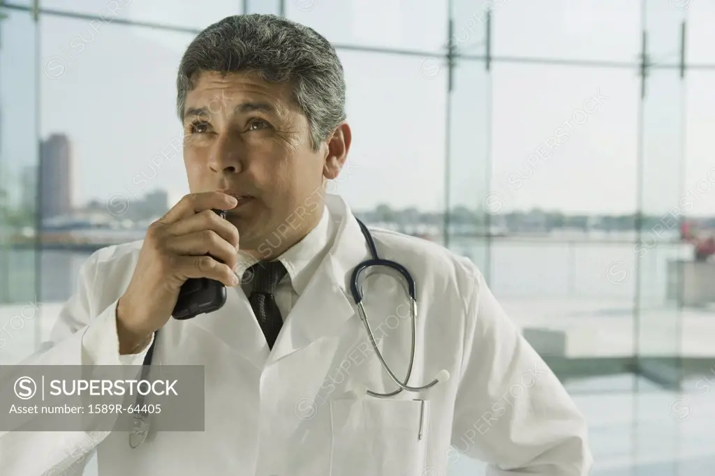 Hispanic doctor in lab coat speaking into dictaphone