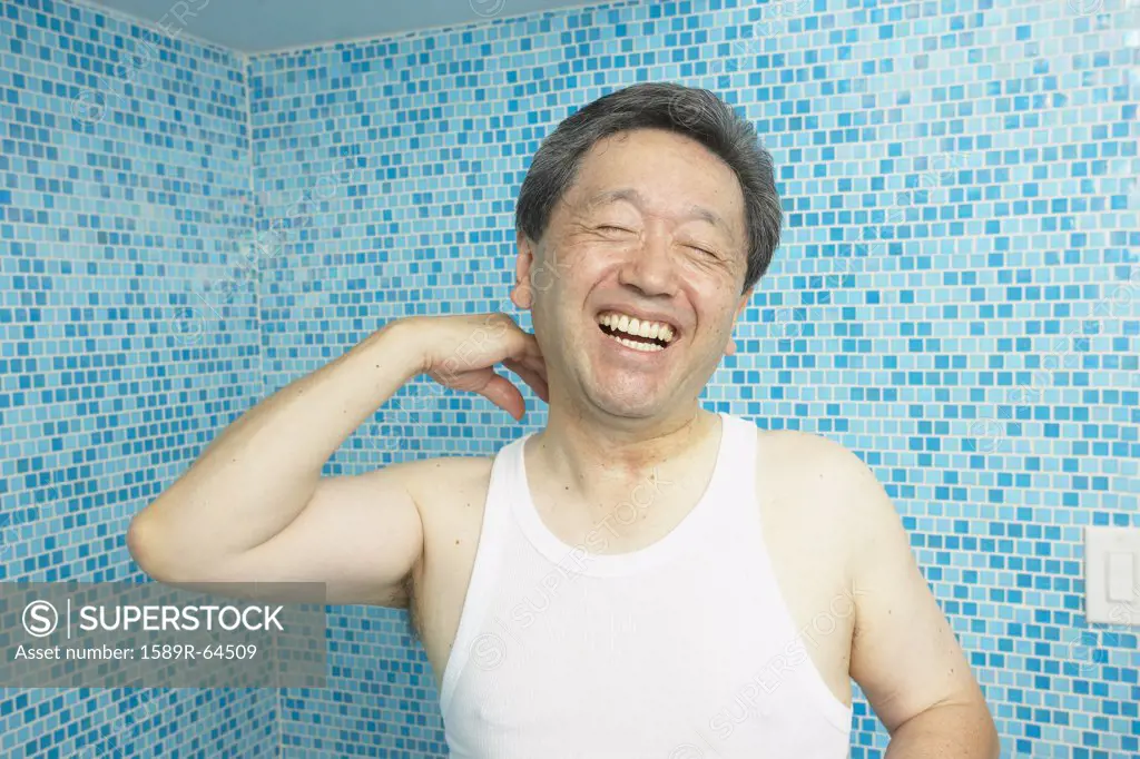 Laughing Asian man in bathroom