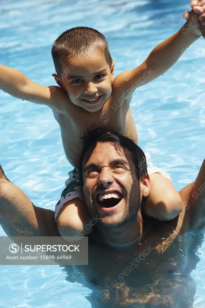 Father giving son piggyback ride in swimming pool
