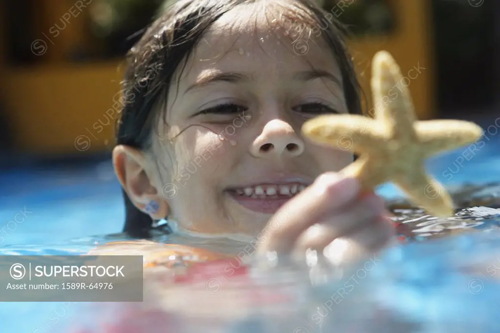 Girl holding starfish in swimming pool