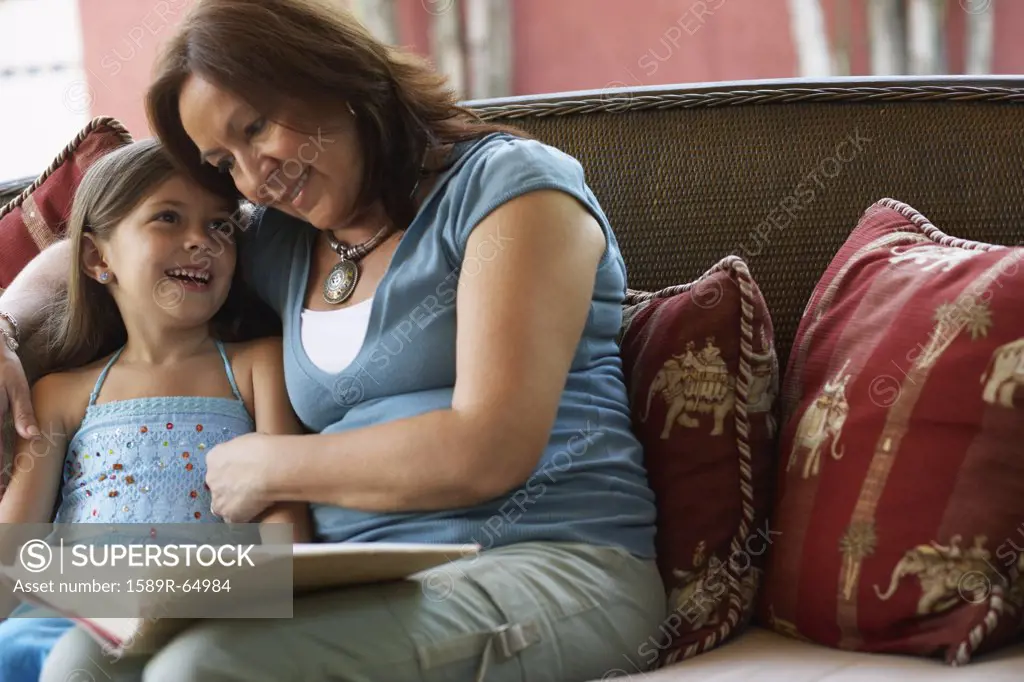 Hispanic grandmother reading to granddaughter