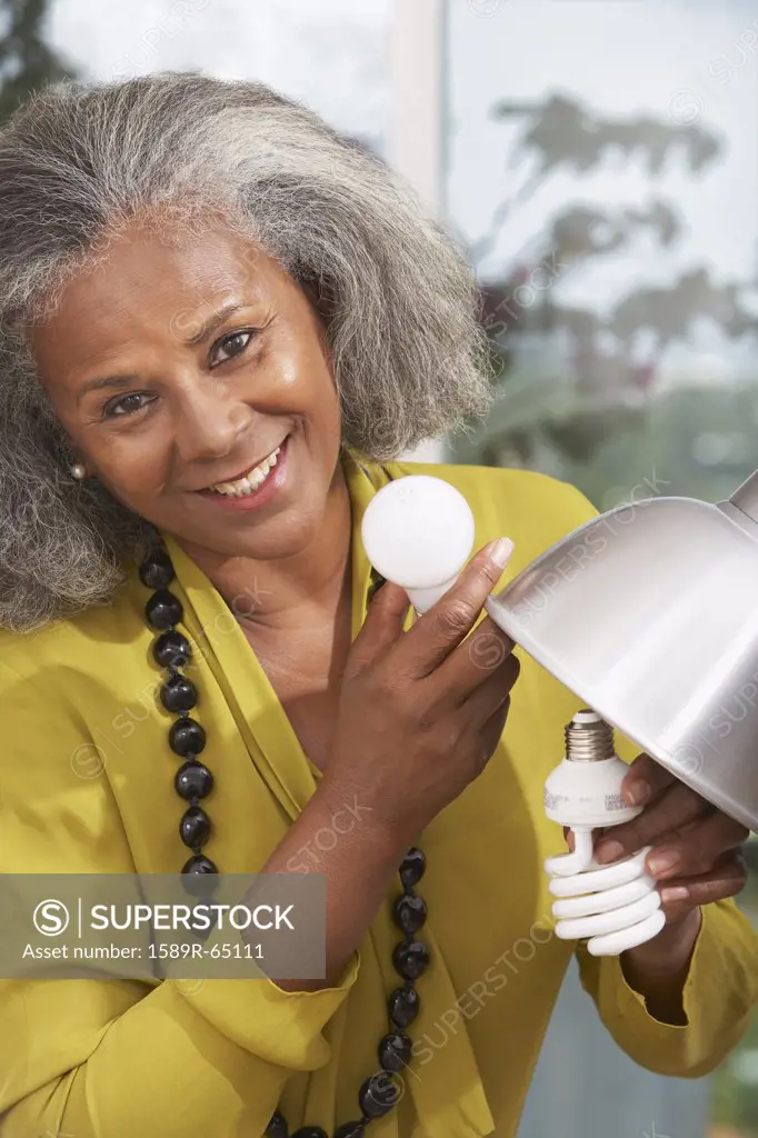 African woman changing lightbulb at home