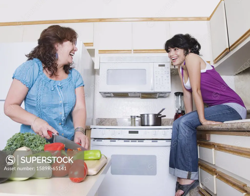 Mother preparing meal and talking to daughter