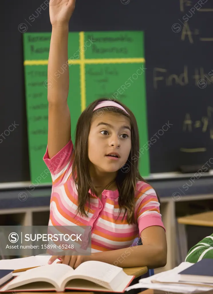 Hispanic girl with arm raised in classroom