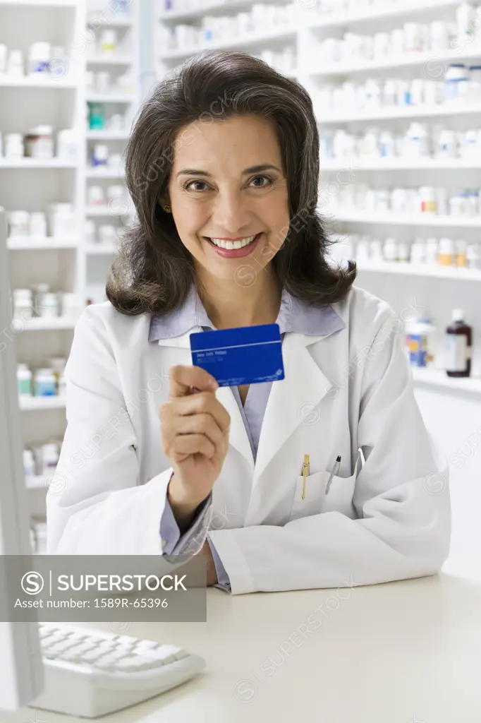 Hispanic pharmacist holding insurance card