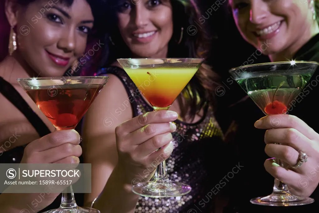Hispanic women drinking cocktails in nightclub