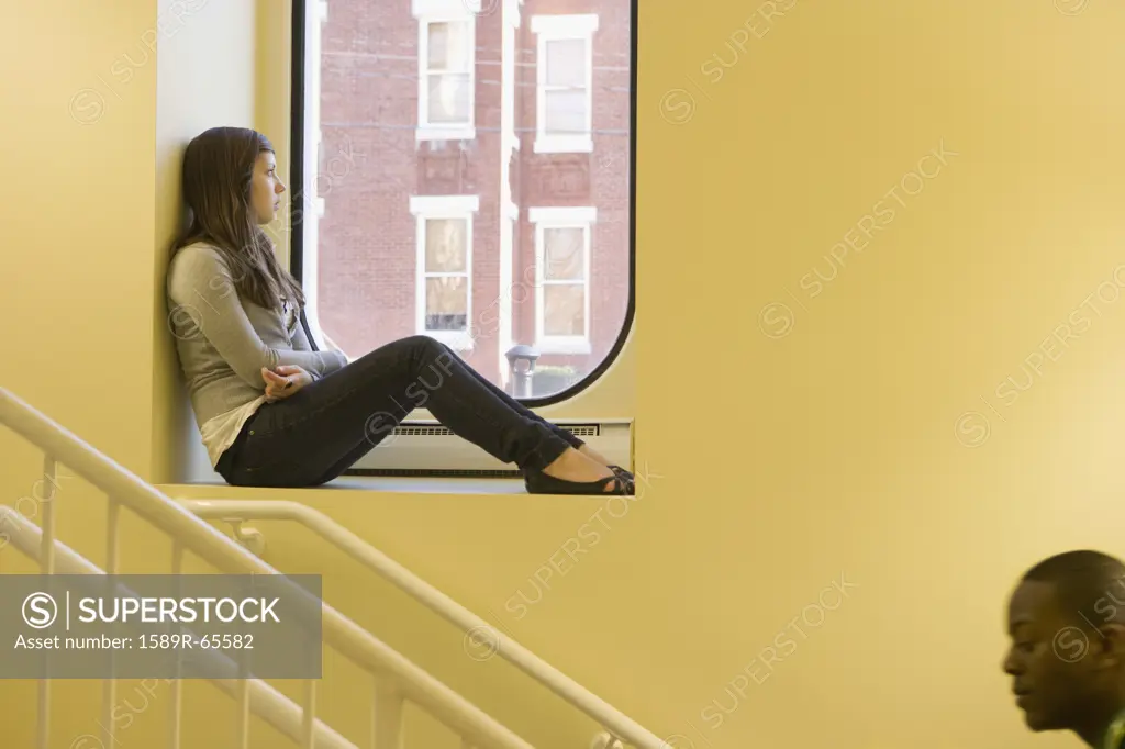 Teenager sitting in window sill
