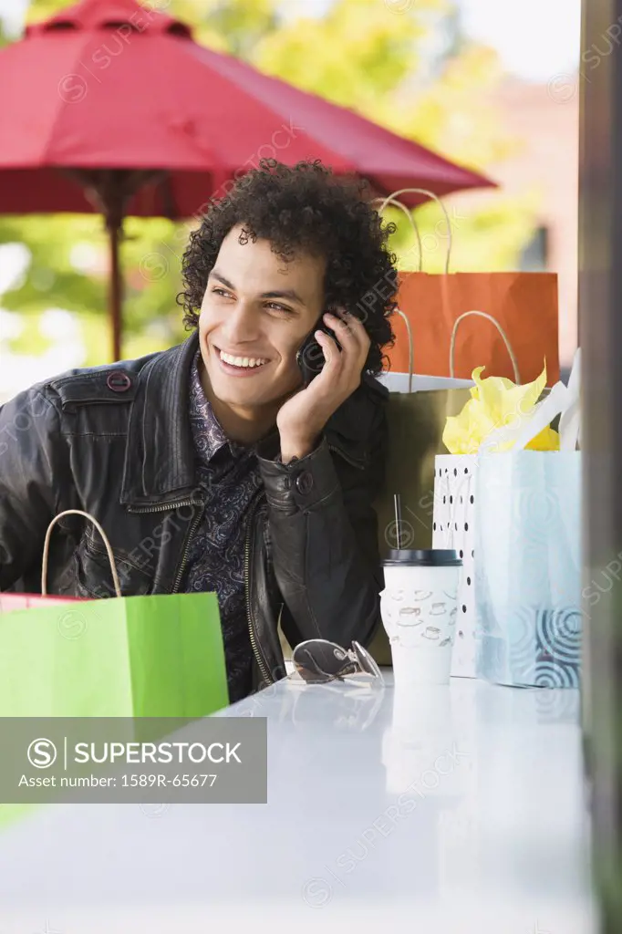 Middle Eastern man with shopping bags talking on cell phone