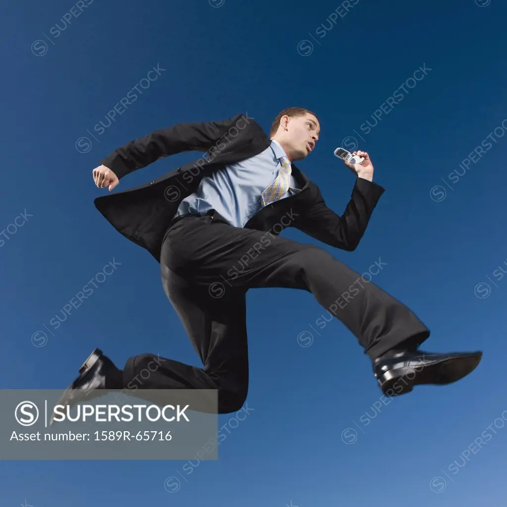 African businessman in mid-air holding cell phone