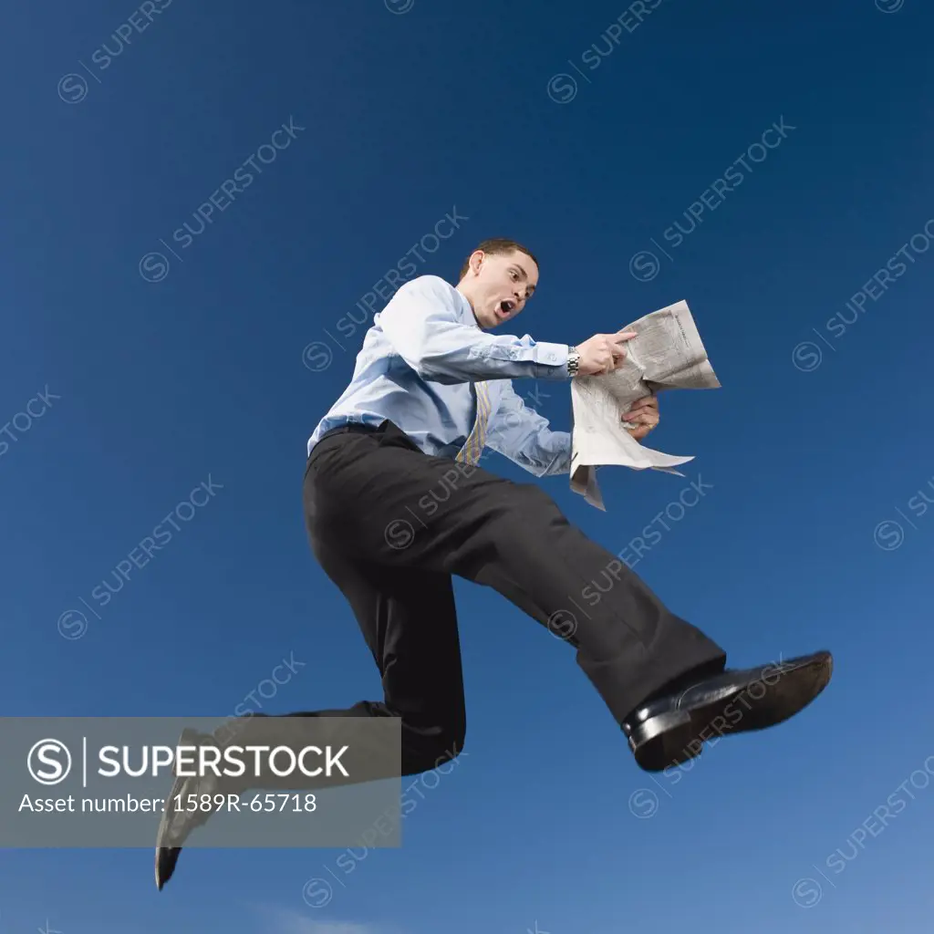 African businessman reading newspaper in mid-air