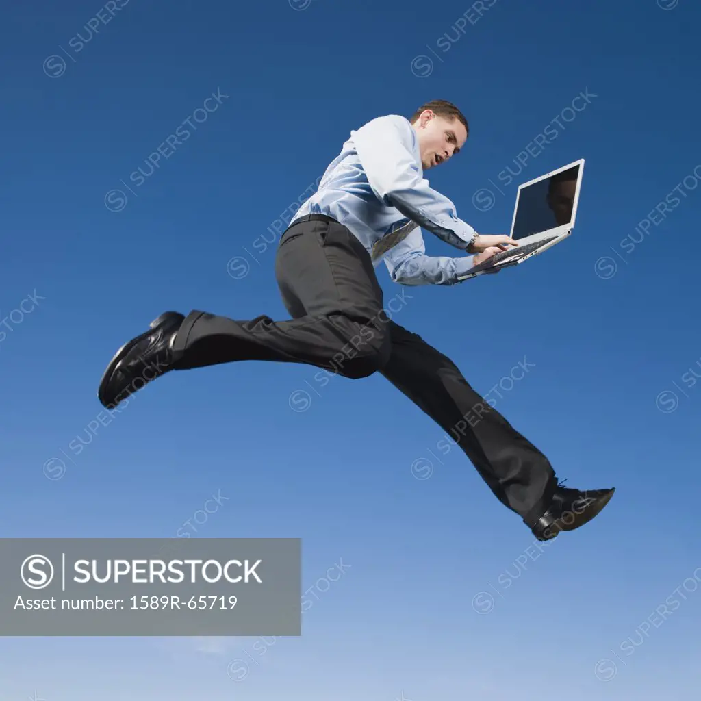 African businessman typing on laptop in mid-air