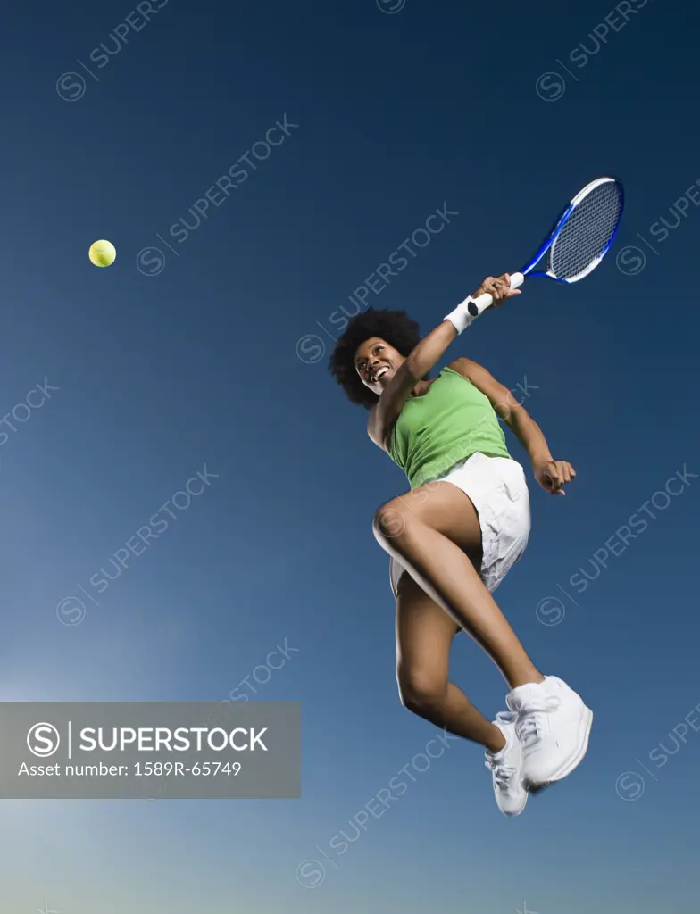 African woman playing tennis in mid-air