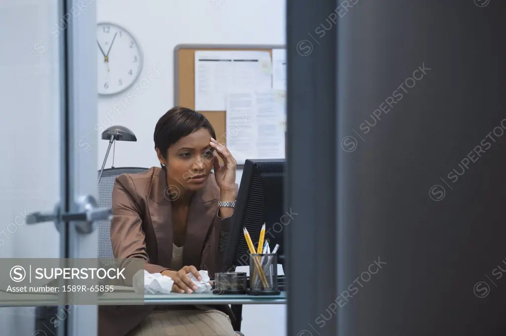 Worried African businesswoman working at computer