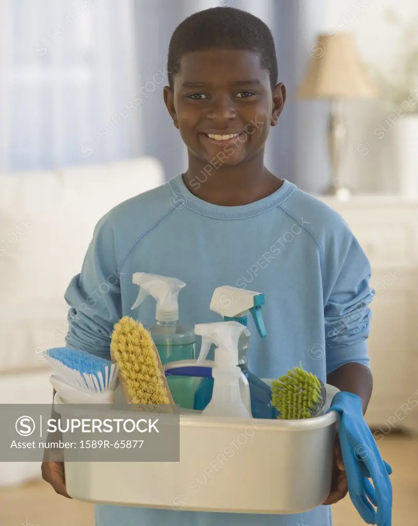African boy holding bucket of cleaning supplies