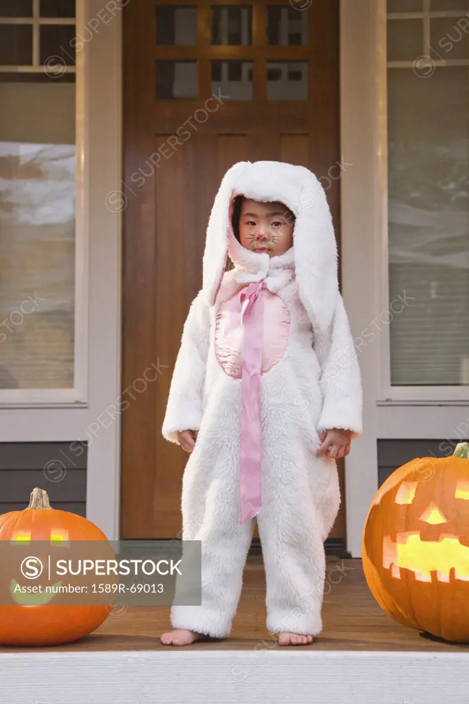 Young Chinese girl in rabbit costume with Halloween pumpkins