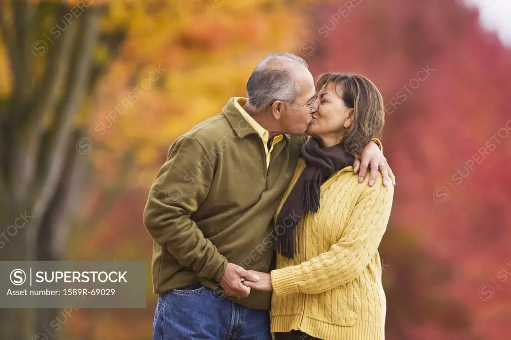Hispanic couple kissing outdoors in autumn