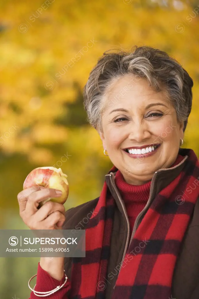 African woman eating apple outdoors in autumn