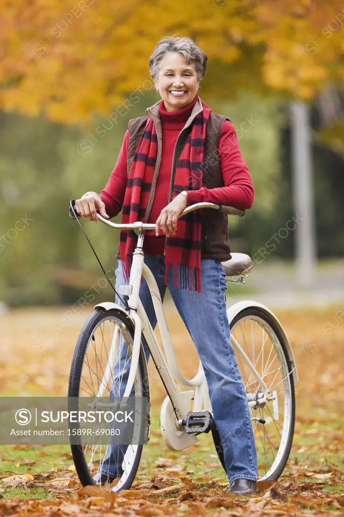 African woman standing with bicycle in park in autumn
