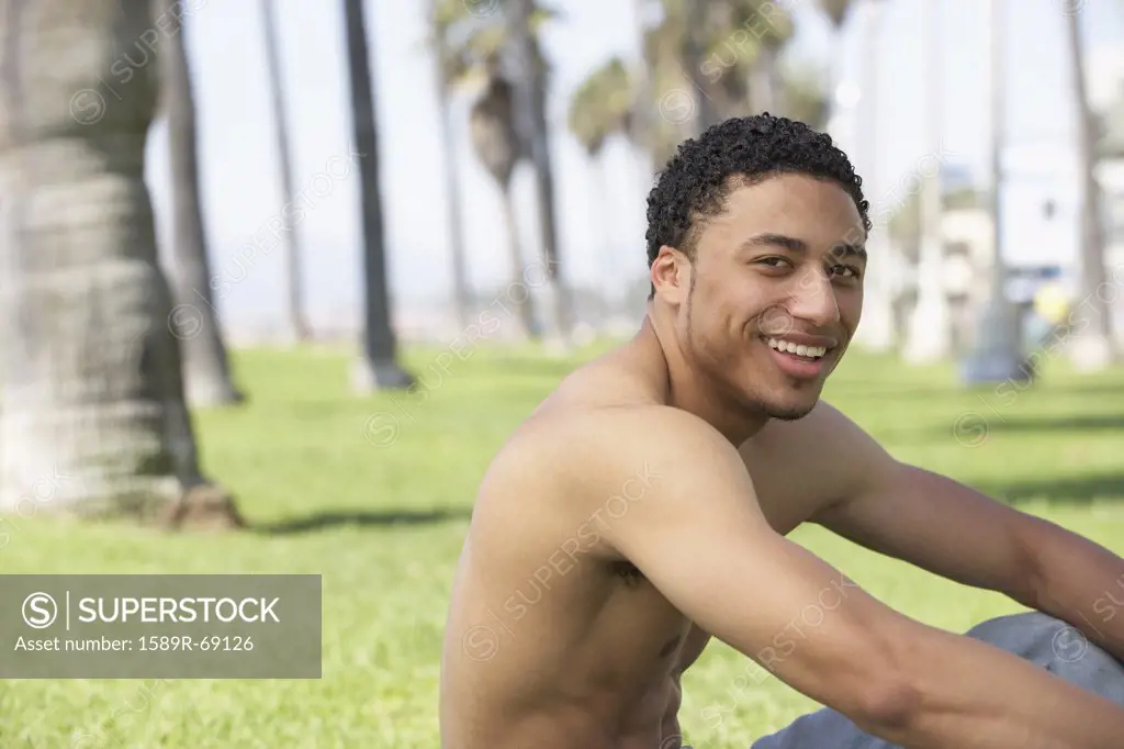 Young mixed race man with bare chest sitting on grass