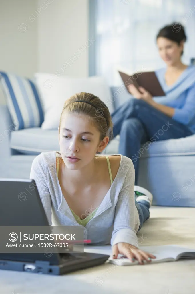 Mixed race girl laying on floor using laptop