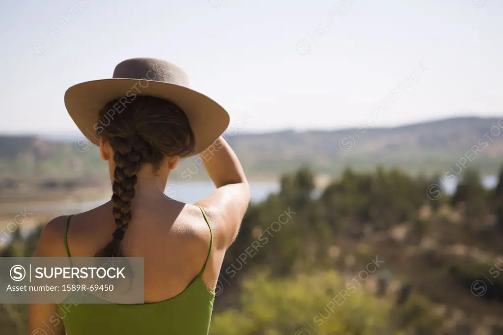 Hispanic woman in hat viewing remote landscape