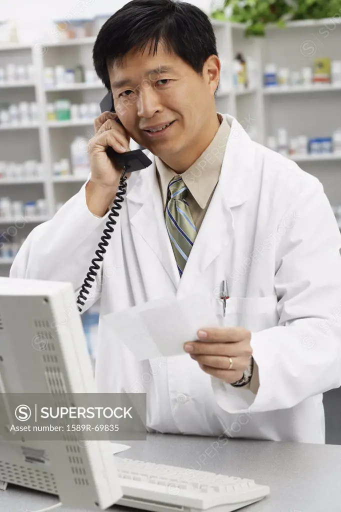 Asian male pharmacist talking on telephone