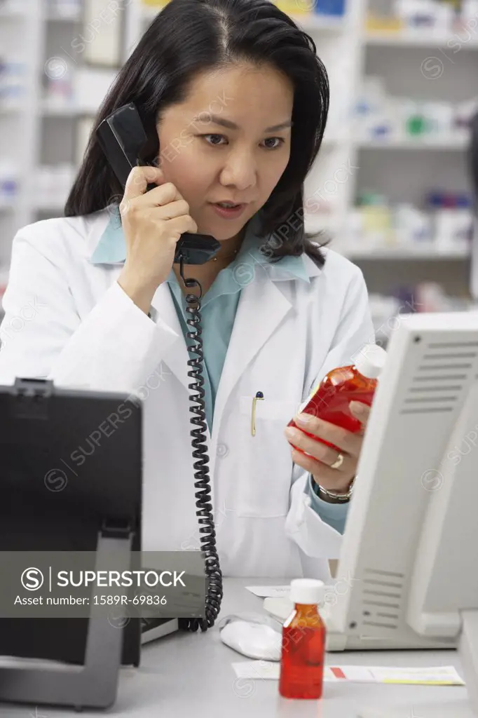 Asian female pharmacist talking on telephone