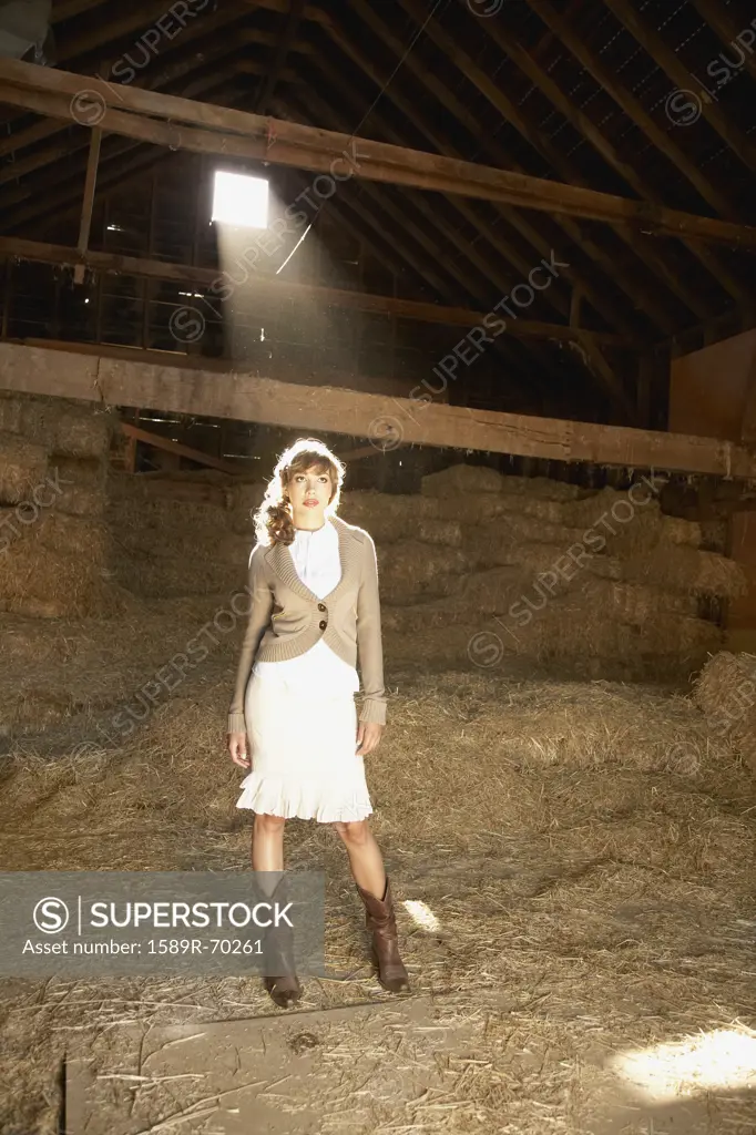 Hispanic woman standing in sunlight in barn