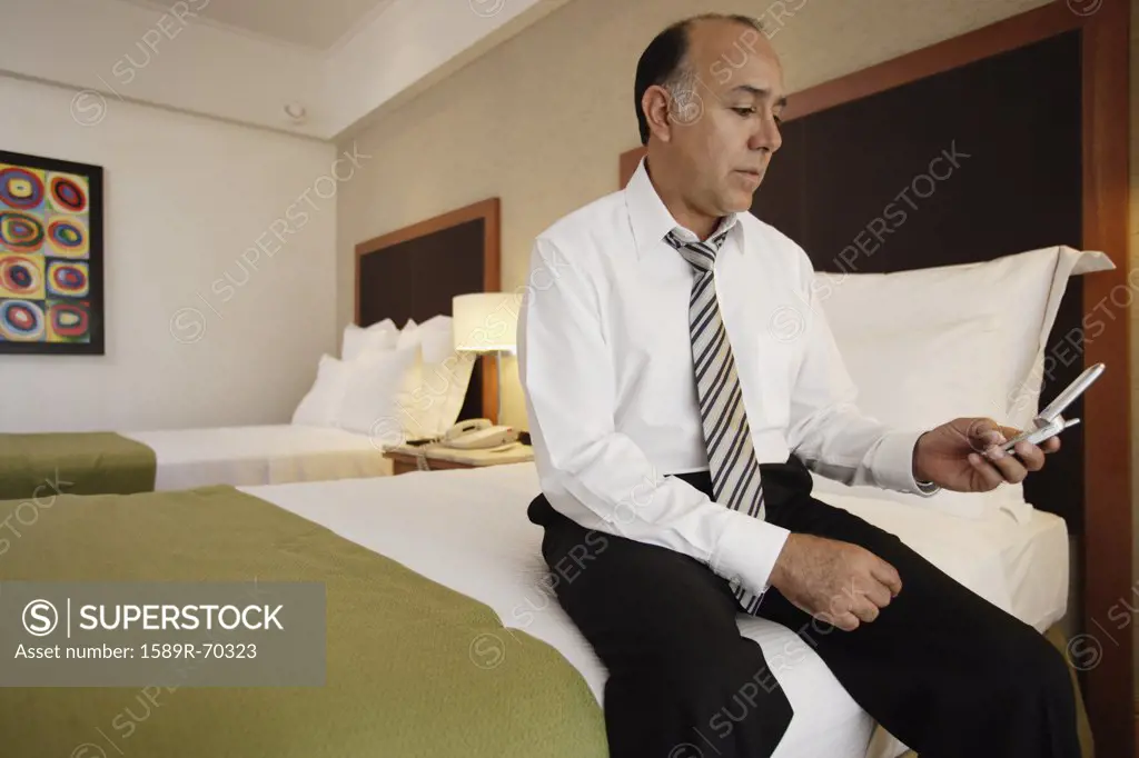 Middle-aged businessman using cell phone in hotel room