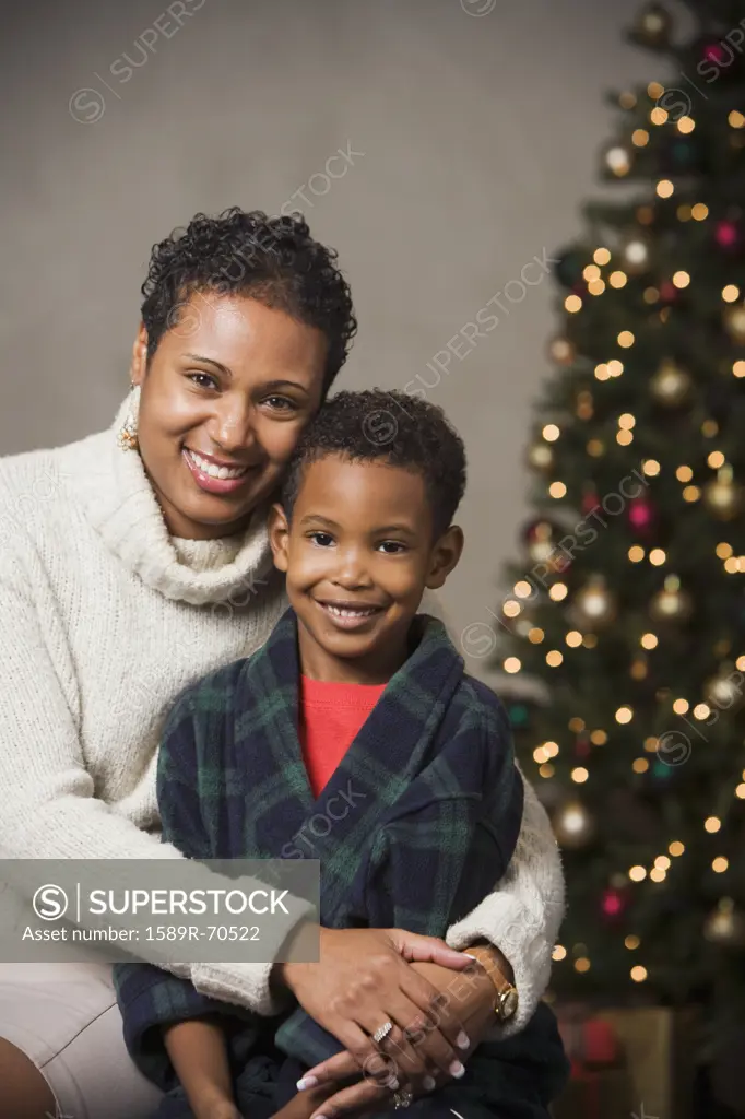 African mother hugging son in front of Christmas tree