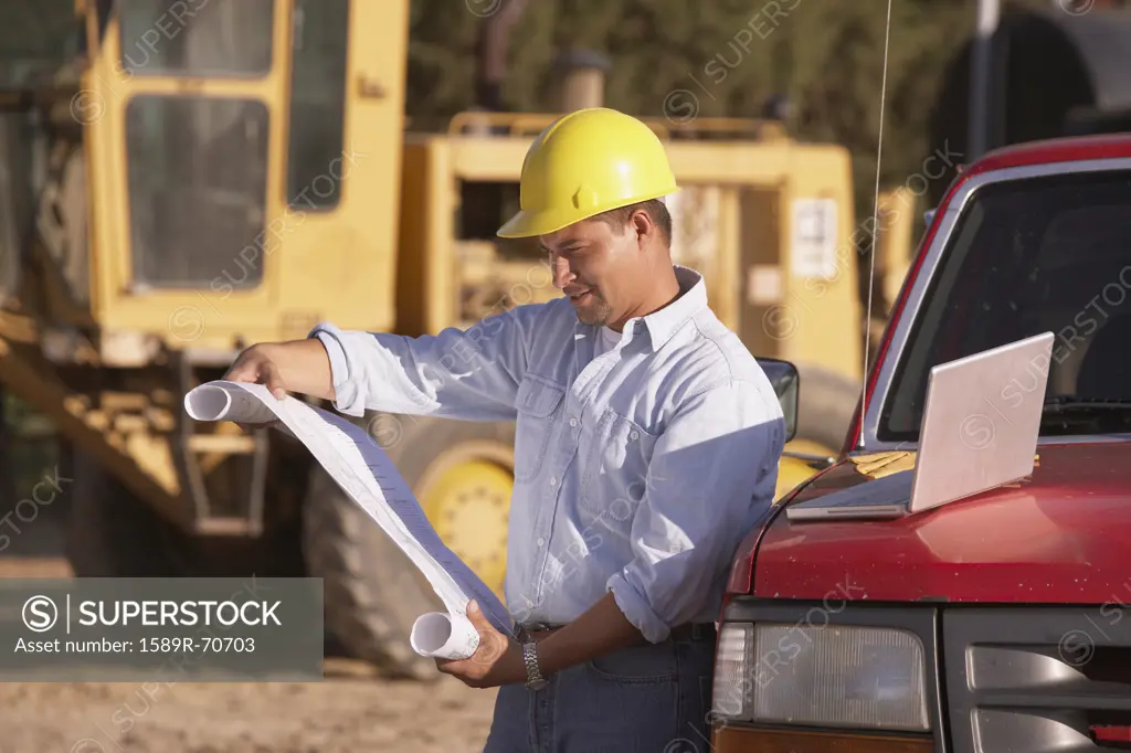 Hispanic male contractor looking at blueprints