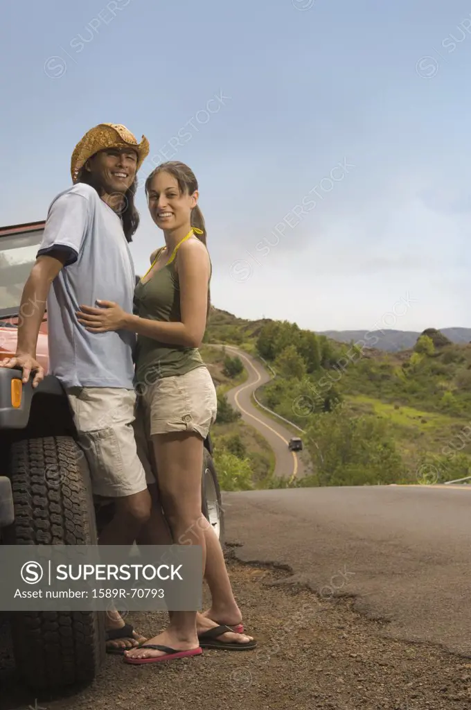 Couple hugging next to jeep on rural road