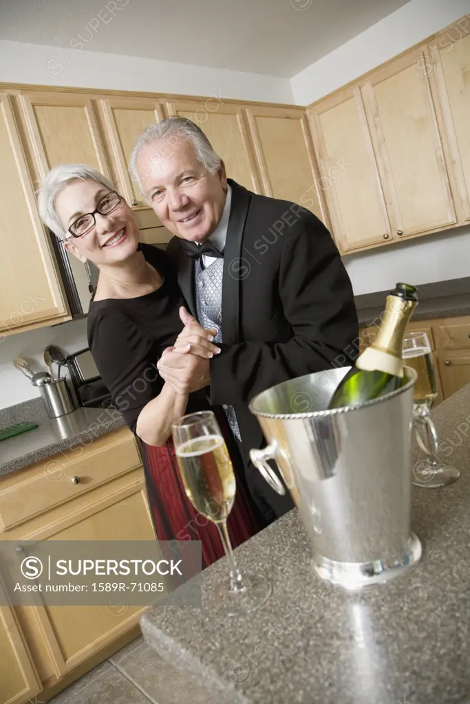 Well dressed senior couple dancing in kitchen