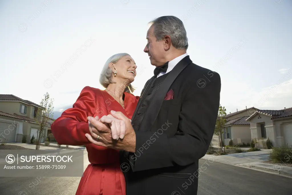 Well dressed senior couple dancing in suburban street 