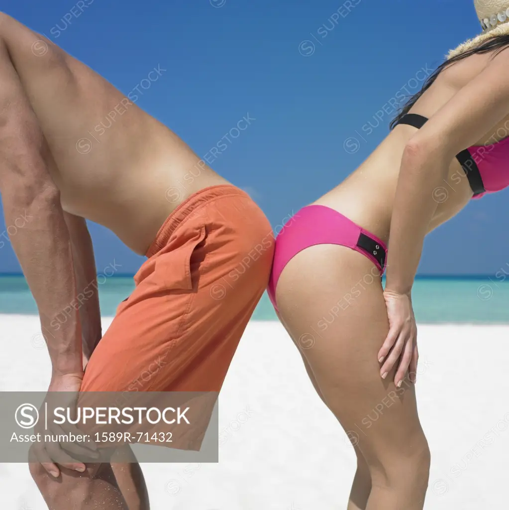 Couple touching rear ends at beach