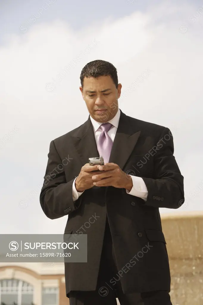 Hispanic businessman looking at cell phone