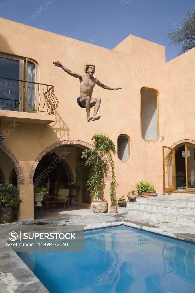 Hispanic man jumping into swimming pool