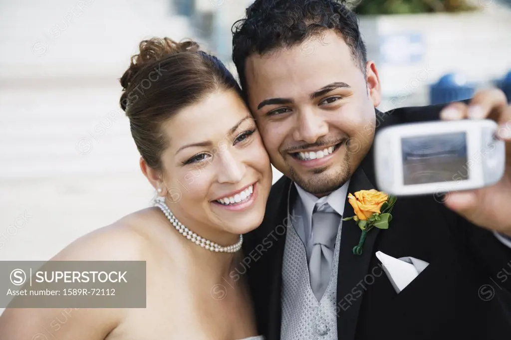 Multi-ethnic bride and groom taking own photograph