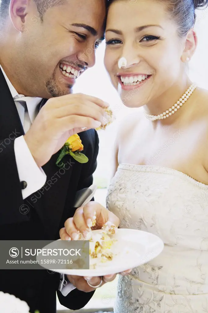 Multi-ethnic bride and groom eating cake