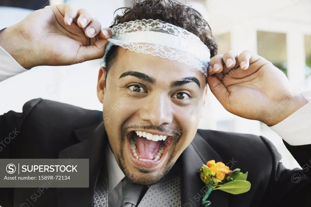 Hispanic groom wearing garter on head